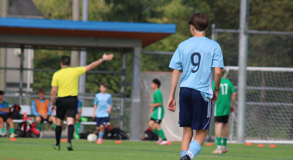 Soccer player watches a referee signal at the BC Summer Games.